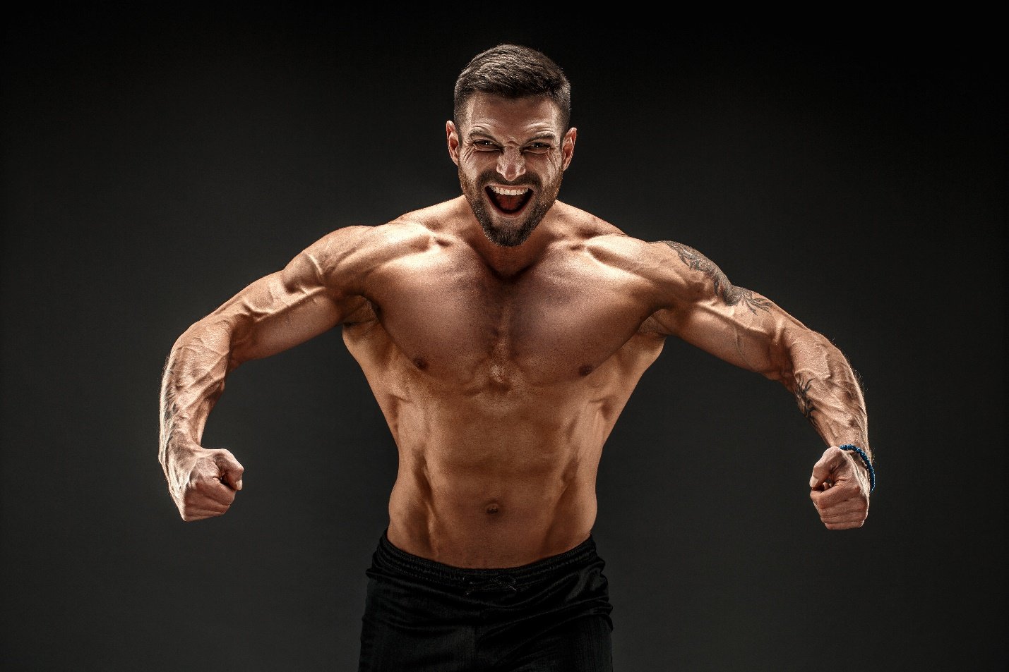a muscular man yelling as he is in a rowing position