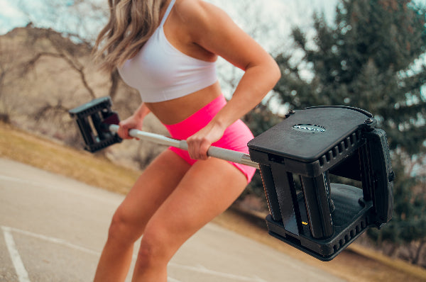 Woman exercising with PowerBlock Pro Series Straight Bar and Pro 50 Adjustable Dumbbells.