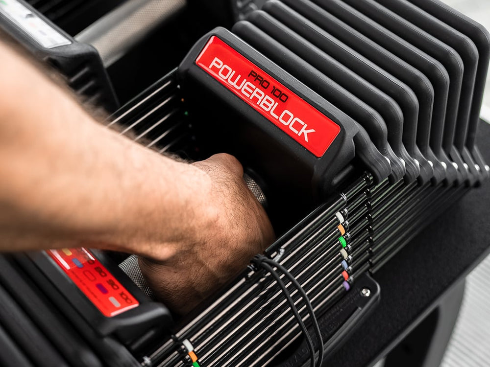 Detailed view of PowerBlock Commercial Pro 100 weight plates and hand grabbing the knurled grip.