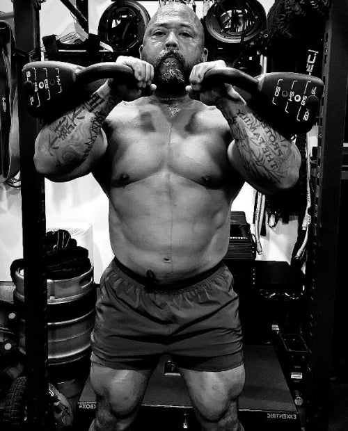 Headshot of trainer 'Da Rulk' holding two PowerBlock Pro adjustable kettlebells in either hand