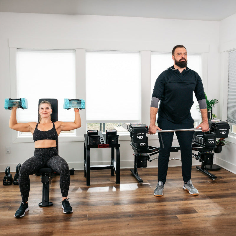 a male and female athletes working out in a clean home gym with their PowerBlock adjustable dumbbells being used on a weight bench and neatly organized.