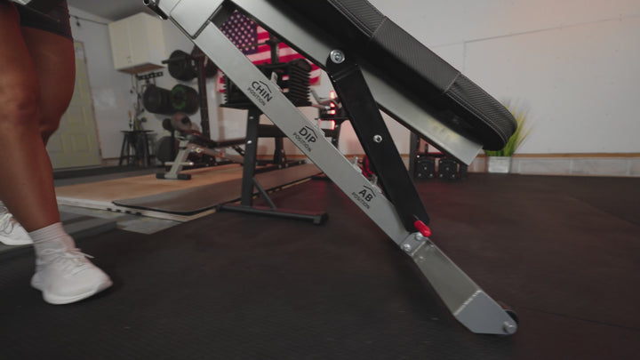 A women demonstrating the PowerBlock Sport-bench and its compatible attachments. The Chin-up and Pull-up, Ab, and Dip attachments.