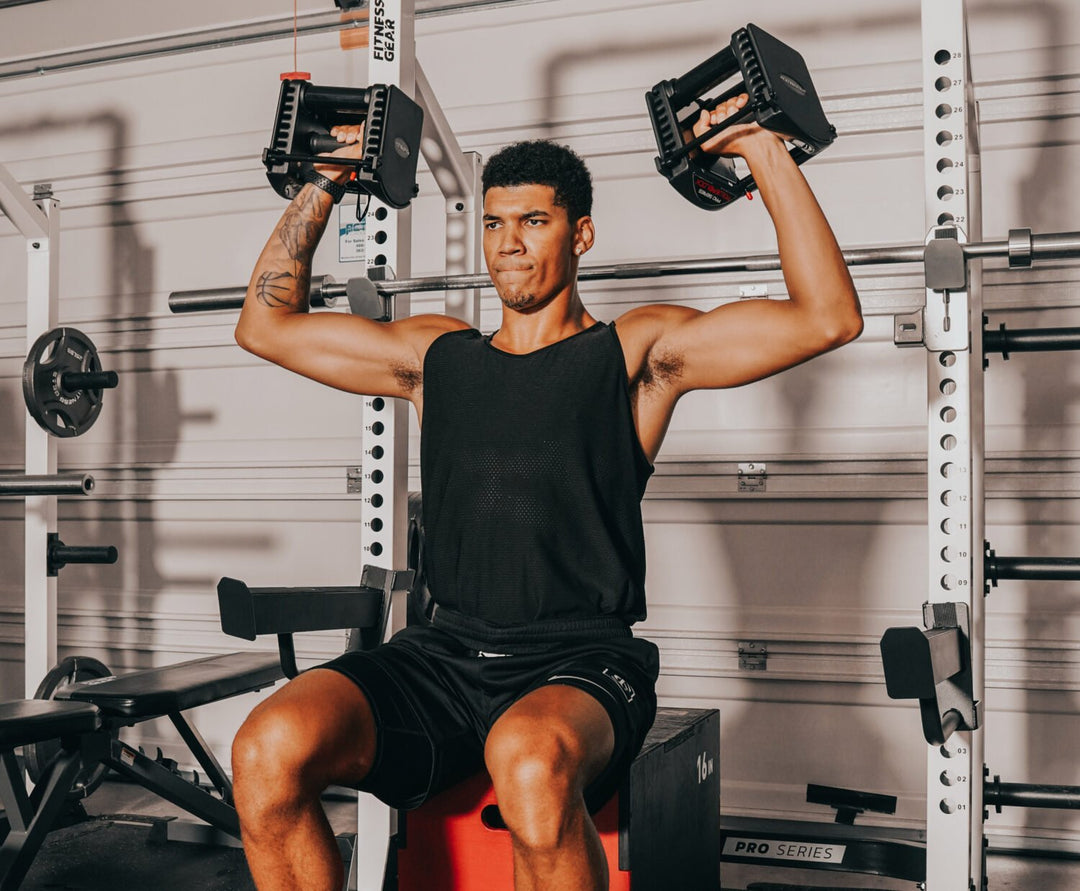 young man working out in garage gym with adjustable dumbbells