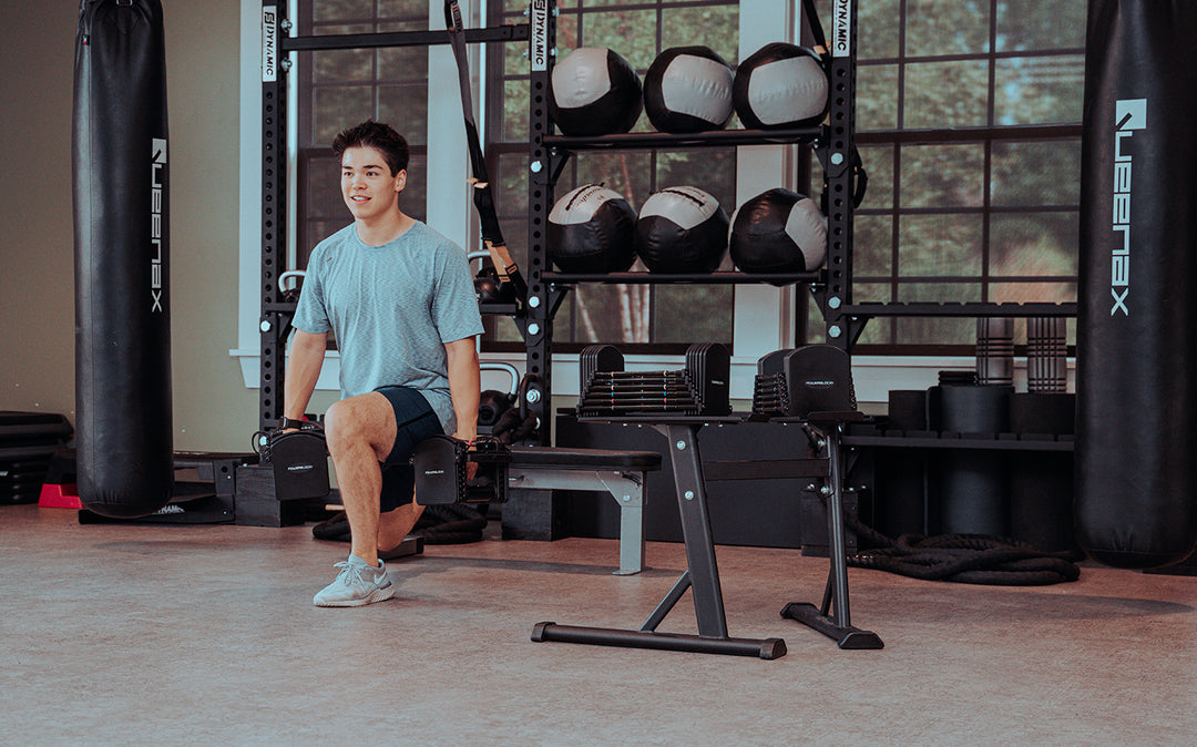 A man demonstrates the proper form for lunges with an adjustable PowerBlock dumbbell in each hand.