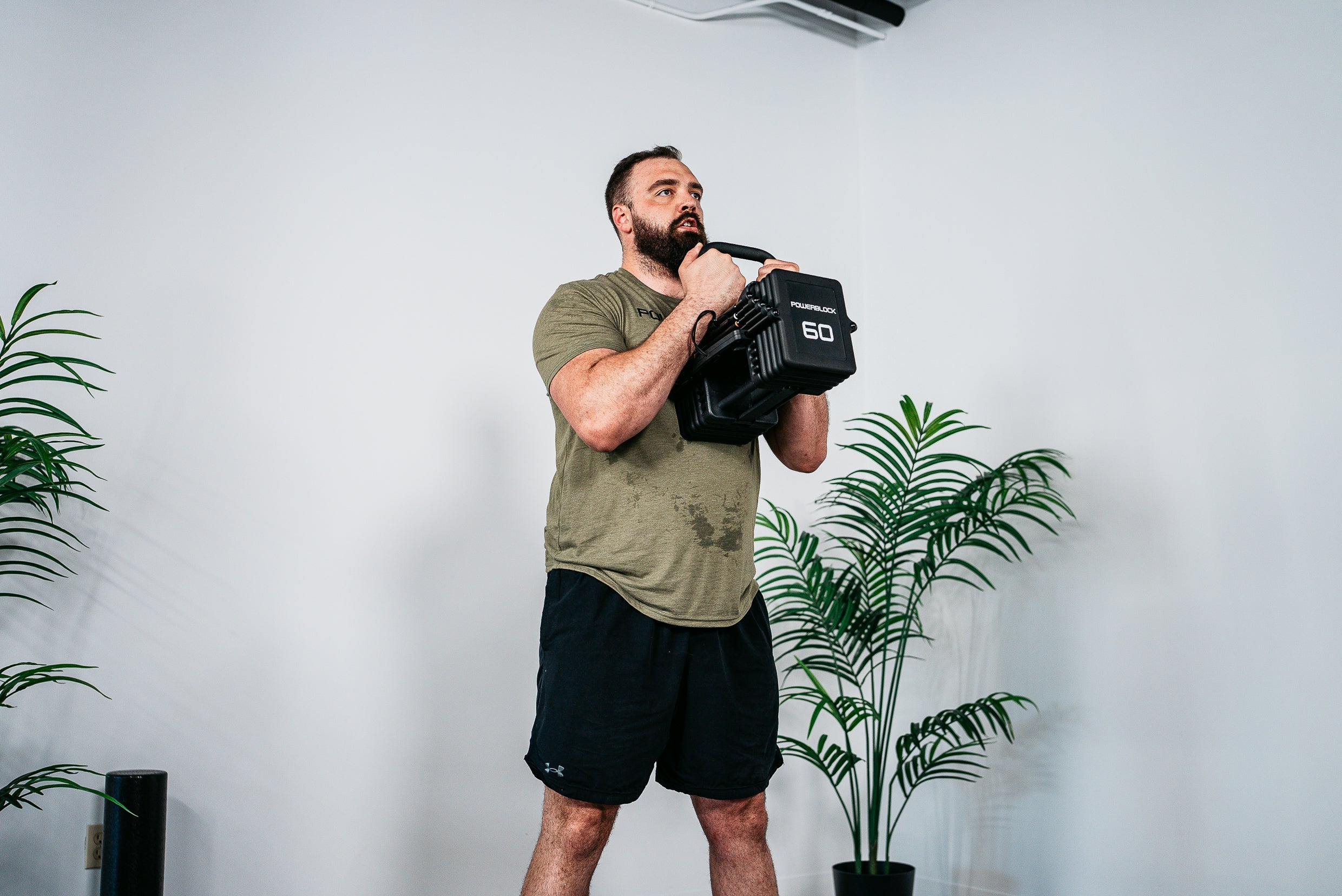 Man performing goblet squats with the PowerBlock Pro 100 EXP Adjustable Dumbbell & the Pro 100 Kettlebell Handle
