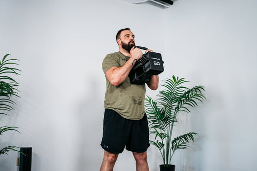 Man performing goblet squats using PowerBlock Pro 100 EXP Adjustable Dumbbells with the Kettlebell Handle Attachment