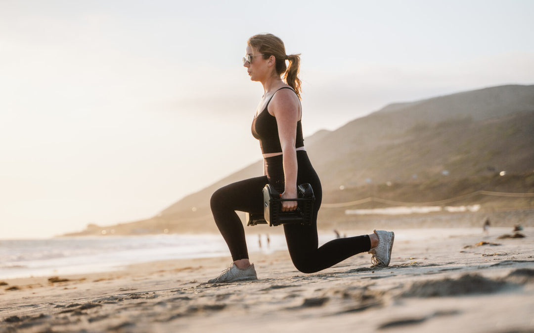 A woman works out on the beach, using her PowerBlock adjustable dumbbells.