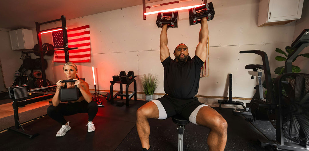 Two athletes workout in a home gym with adjustable dumbbells and kettlebells with other common home gym equipment.