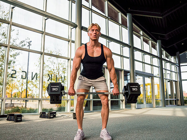 fit athlete in a commercial gym with PowerBlock adjustable barbell