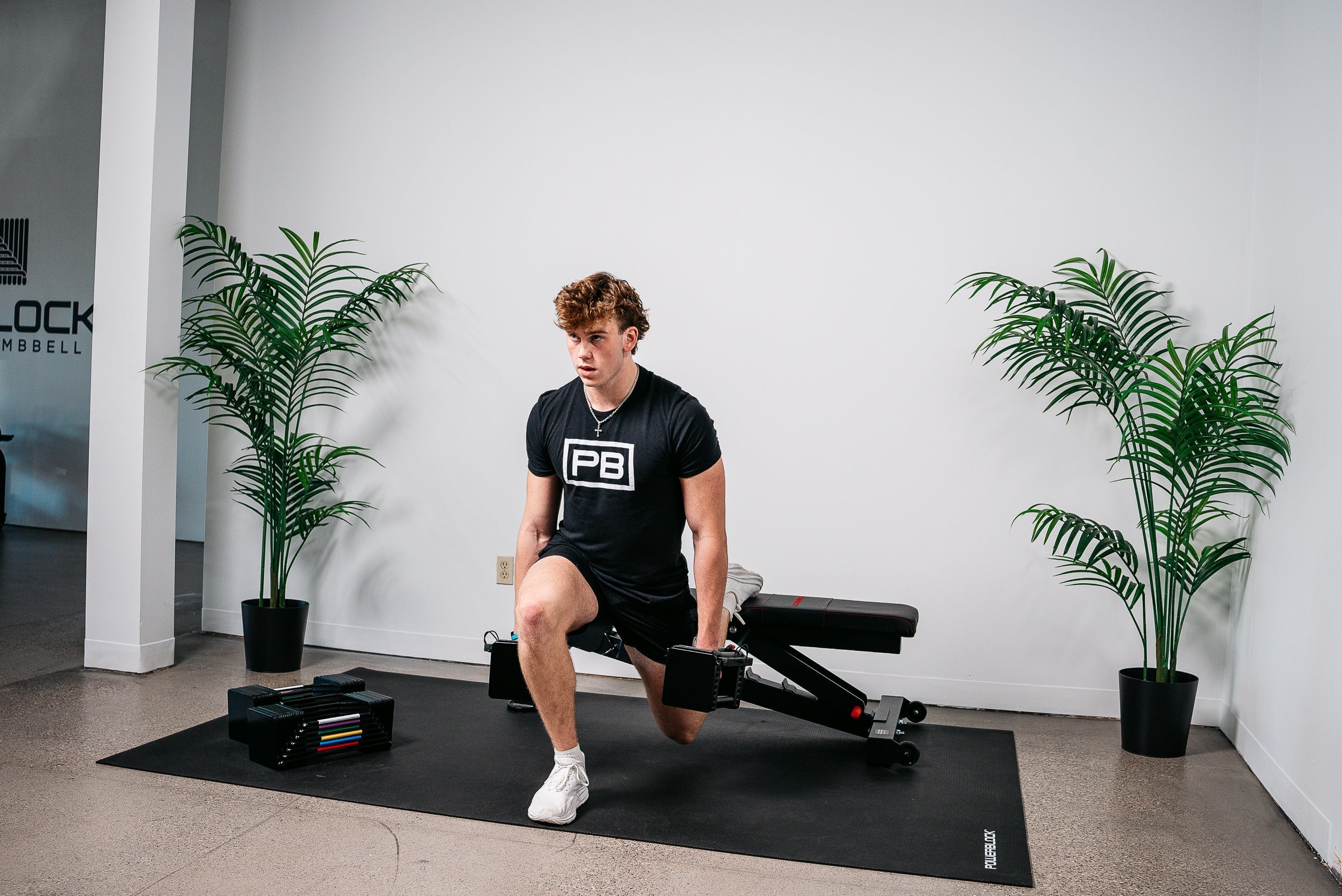 Man performing Bulgarian split squats using the PowerBlock Elite USA 90EXP Adjustable Dumbbell and Power Bench 2.0