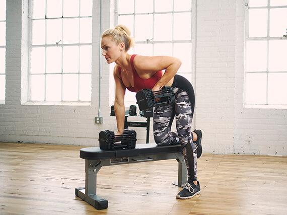 A female athlete works out indoors with her PowerBlock adjustable dumbbells.