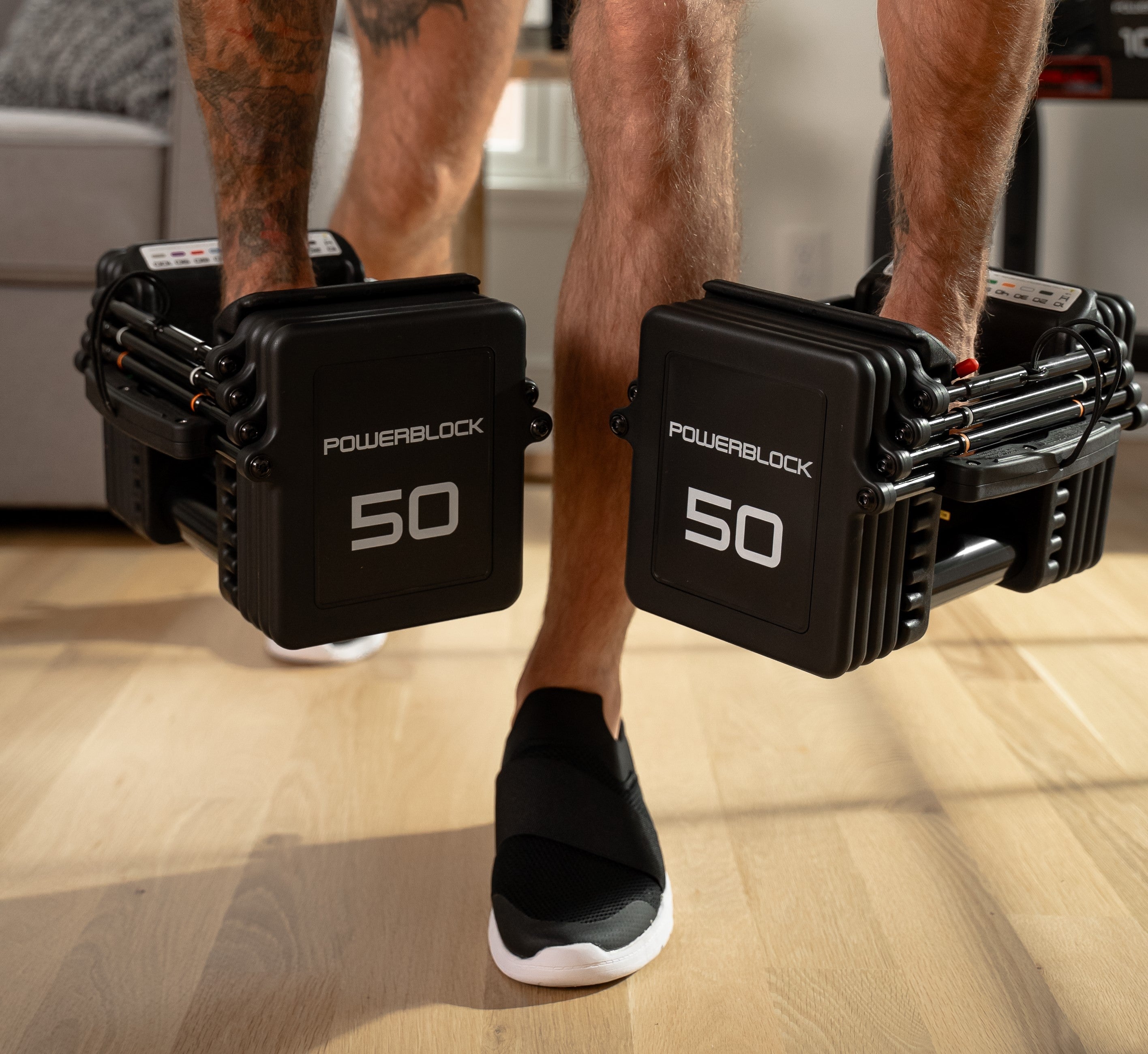 pair of 50 adjustable dumbbells being lifted in an rdl move in a small home gym