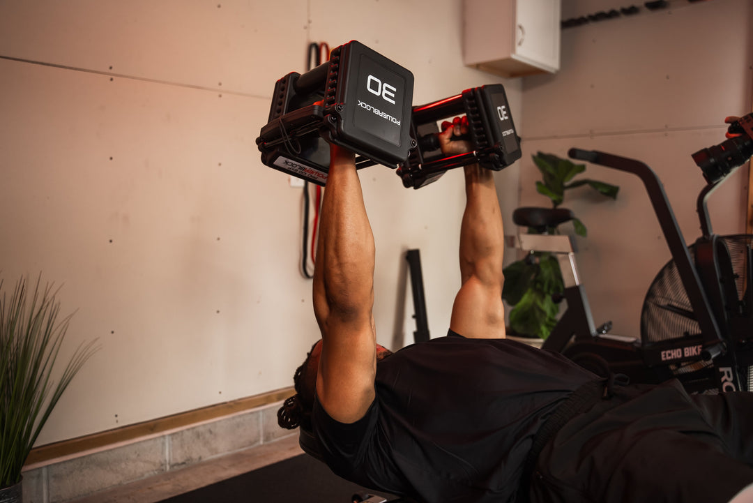 Man performing a dumbbell bench press using the PowerBlock Pro 100 EXP Adjustable Dumbbell that goes from 5-100lbs in 5lb increments. 