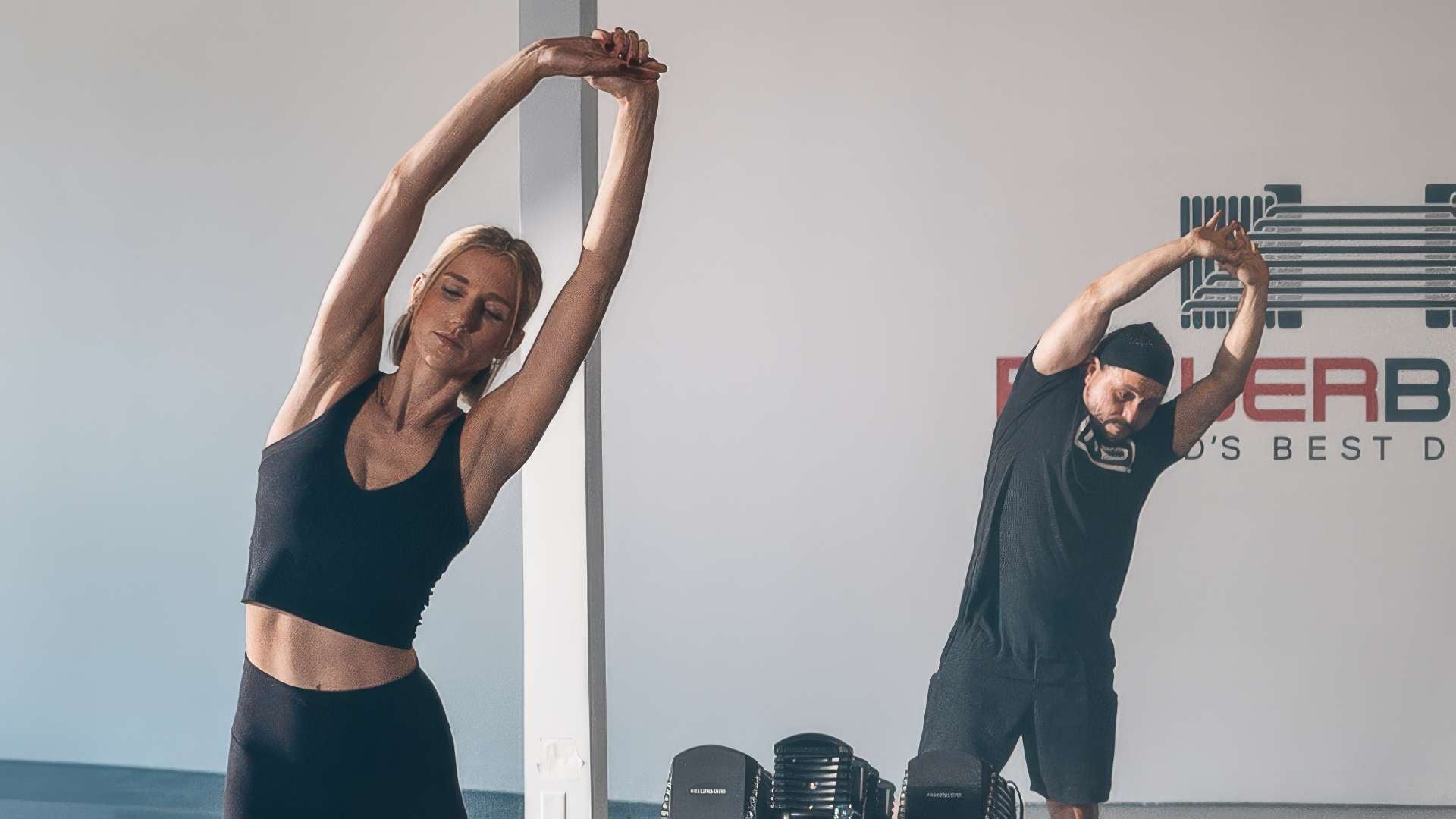 athletes in a fitness studio stretch during a warm up before working out with weights