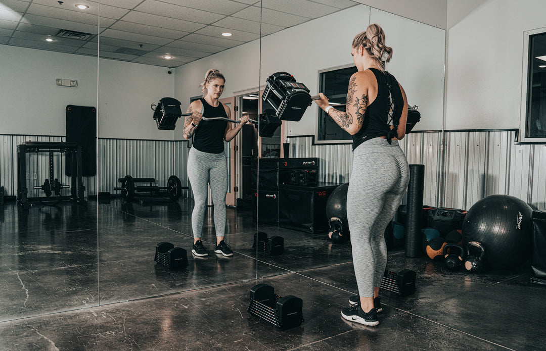 Woman exercising with PowerBlock Pro Series EZ Curl Bar and Pro 50 Adjustable Dumbbells.