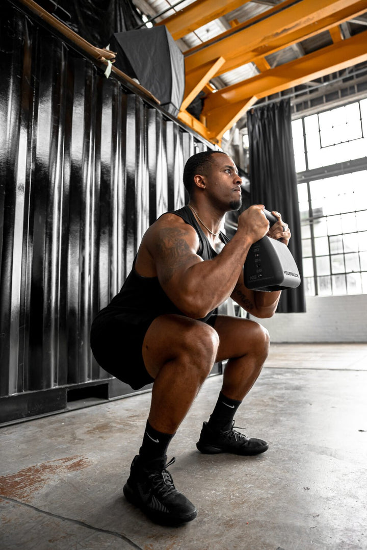 Man squatting with the Pro Adjustable Kettlebell 18-35 lb.