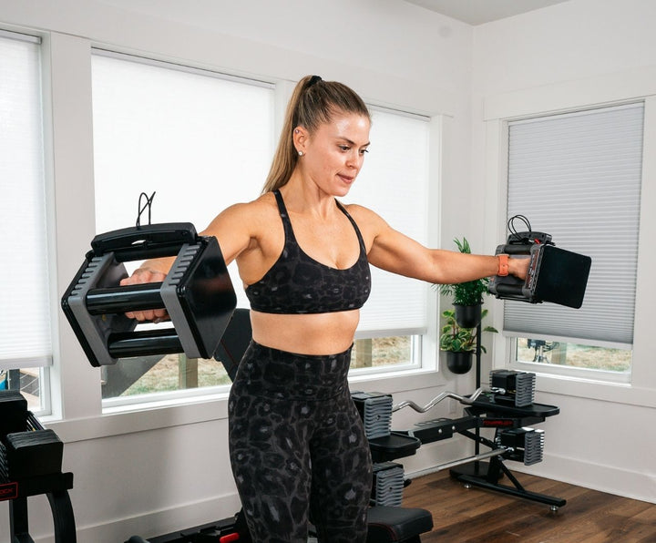 Woman doing lateral raises with Elite EXP Stage 1 Dumbbells