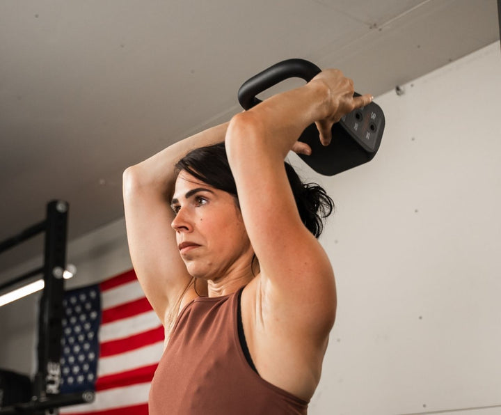 Woman in home gym using the light kettlebell for tricep dips