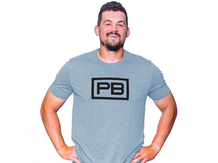 Man wearing a Like You Blue PowerBlock Mens Tee that features a red PB logo.