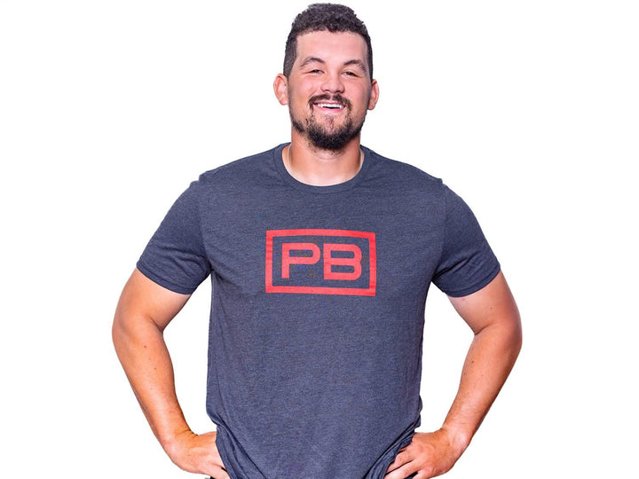 Man wearing a Rebel Blue PowerBlock Mens Tee that features a red PB logo.