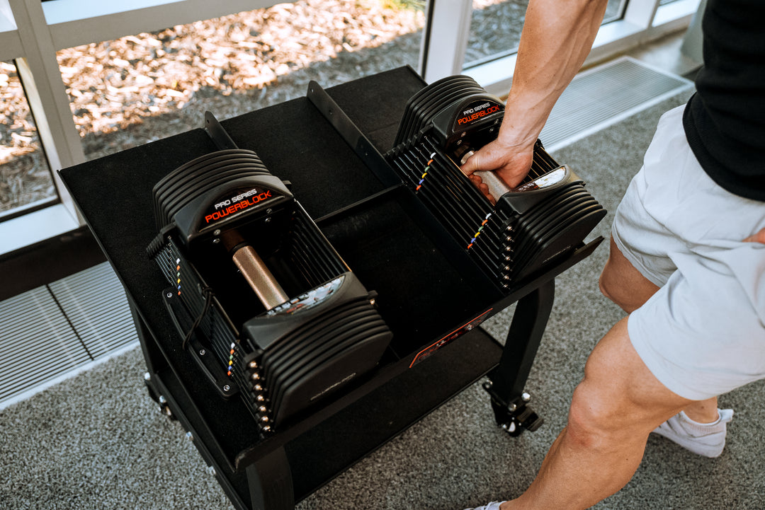 A man reaching for a PowerBlock Commercial Pro 50 Adjustable Dumbbell.