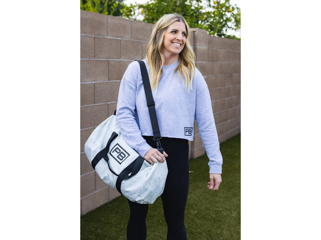 Woman standing with white PowerBlock Duffle Bag on her shoulder.