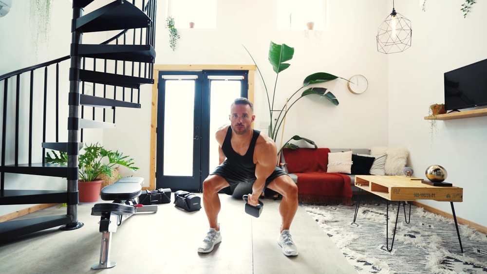 A man using a PowerBlock adjustable kettlebell to do a clean and press