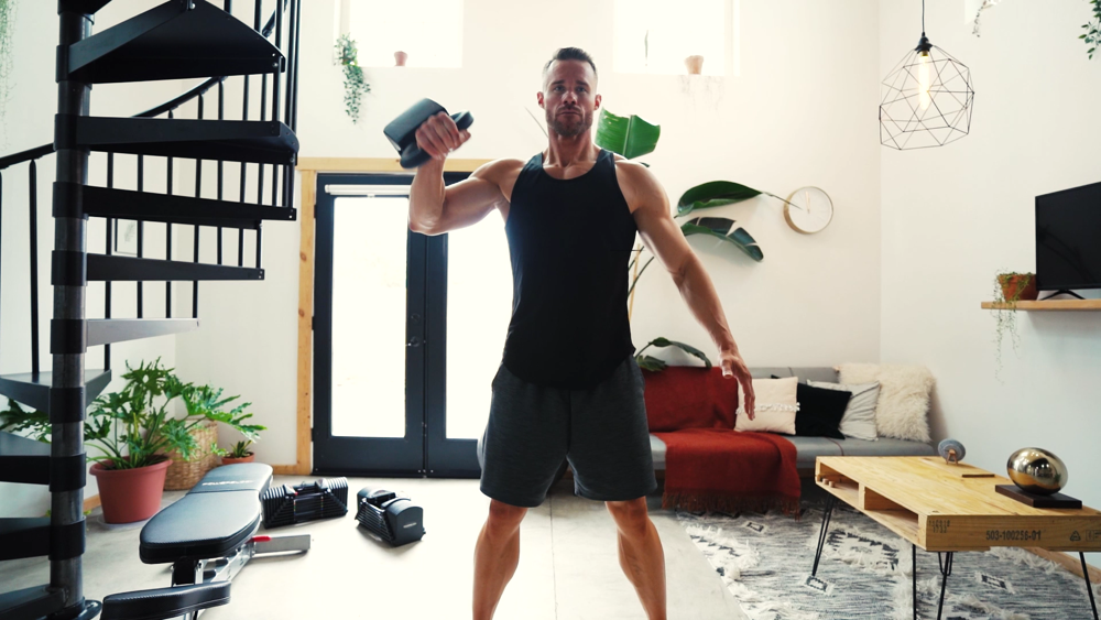 A man performing a snatch with a PowerBlock adjustable kettlebell