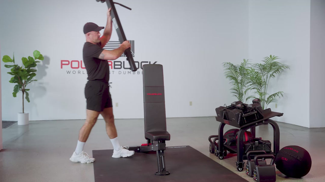 Athlete using the PowerBlock Powerbench 2.0 Adjustable Bench. Takes out a pull up bar and does pull ups. Insert a dip attachment and performs dips. Finally inserts an ab attachment and performs crunches on the bench. 