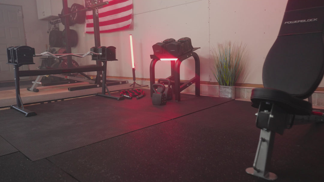 The PowerBlock adjustable kettlebell being used for swings, halos, and changing weights by a female athlete in a garage gym 