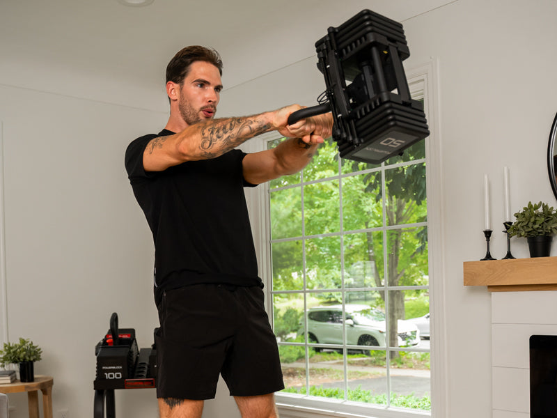 a fit man using an adjustable kettlebell with heavy weight stack for a kettlebell swing excercise