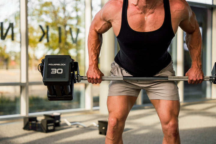 Man exercising with PowerBlock Pro 100 Straight Bar and PowerBlock Pro 100 EXP Adjustable Dumbbells.