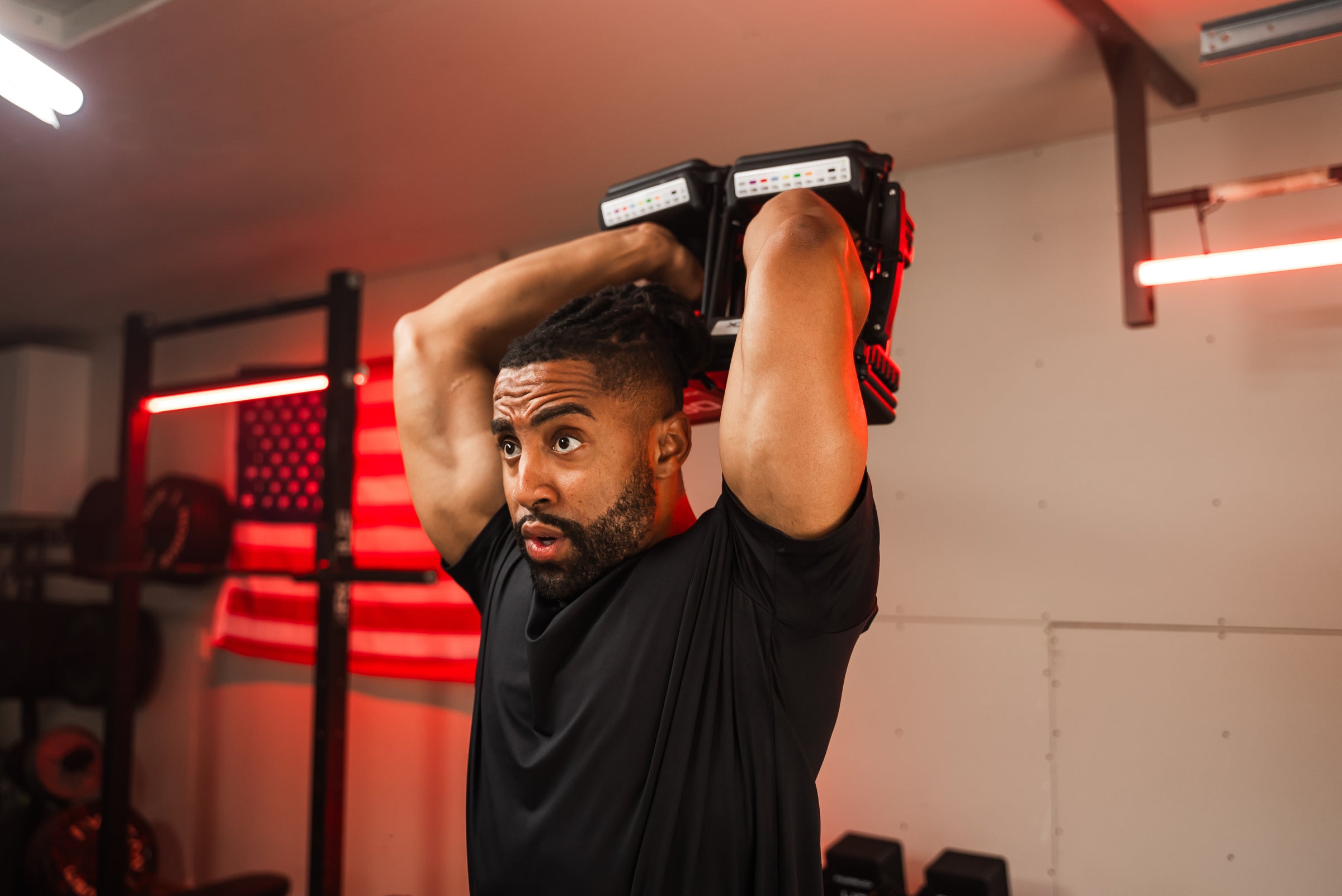 A man doing overhead tricep extensions using a pair of PowerBlock Pro 100 EXP dumbbells