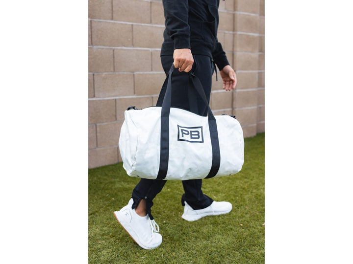 Man carrying white PowerBlock Duffle Bag.