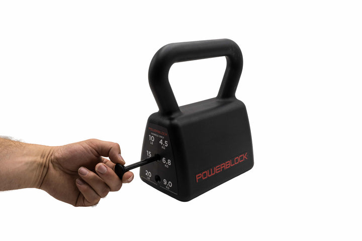 A hand holding the black magnetic selector pin and placing it into the middle weight of 15 lbs. 
