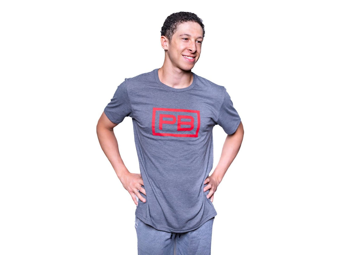 Man wearing a Terrain Grey PowerBlock Mens Tee that features a red PB logo.