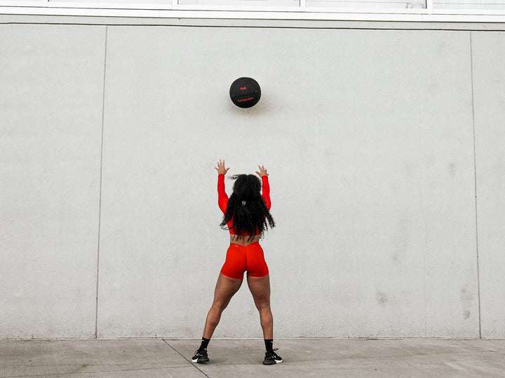 5lb wall ball being thrown up high against a concrete wall by a strong female athlete