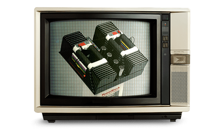 PowerBlock adjustable dumbbells shown on an old-fashioned TV set from the 1990s.