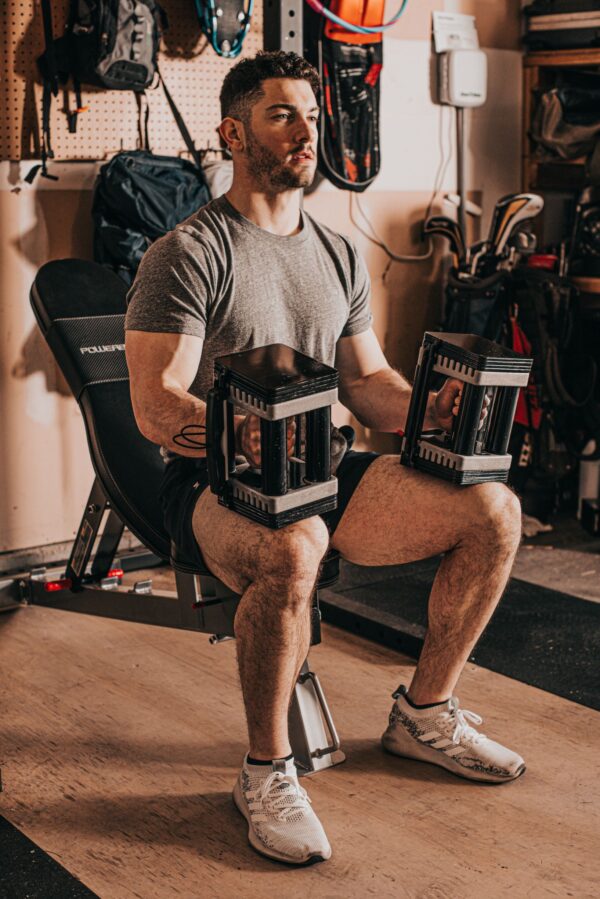 Man in garage gym using Elite USA adjustable dumbbells