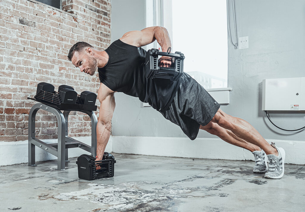 A man holds himself up on one PowerBlock adjustable dumbbell, pulling another dumbbell to his chest.